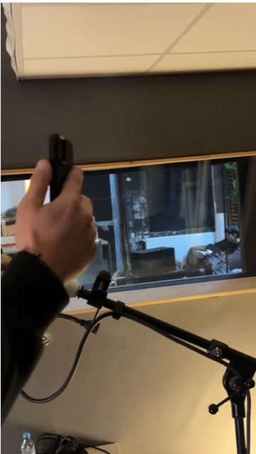 Blick in ein Aufnahmestudio_ im Vordergrund hält eine Hand ein Smartphone